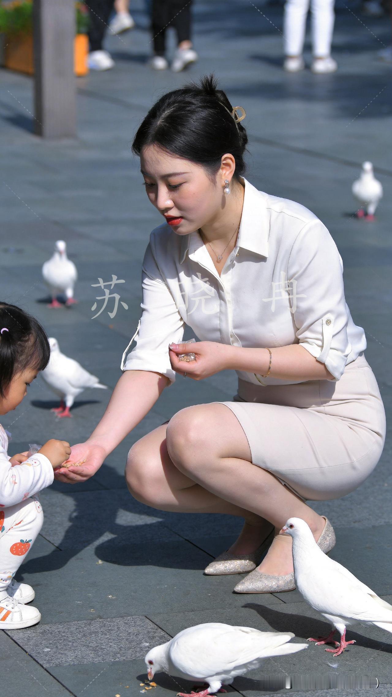 城市广场的石板路上，常有一抹温柔的身影。她时常牵着小女儿的手，习惯性蹲下身，掌心