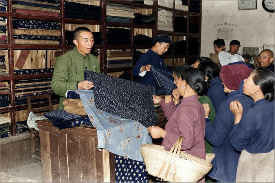 1958年，南京六合县供销社，一位售货员正展开一块印花布给顾客挑选，几位女性顾客