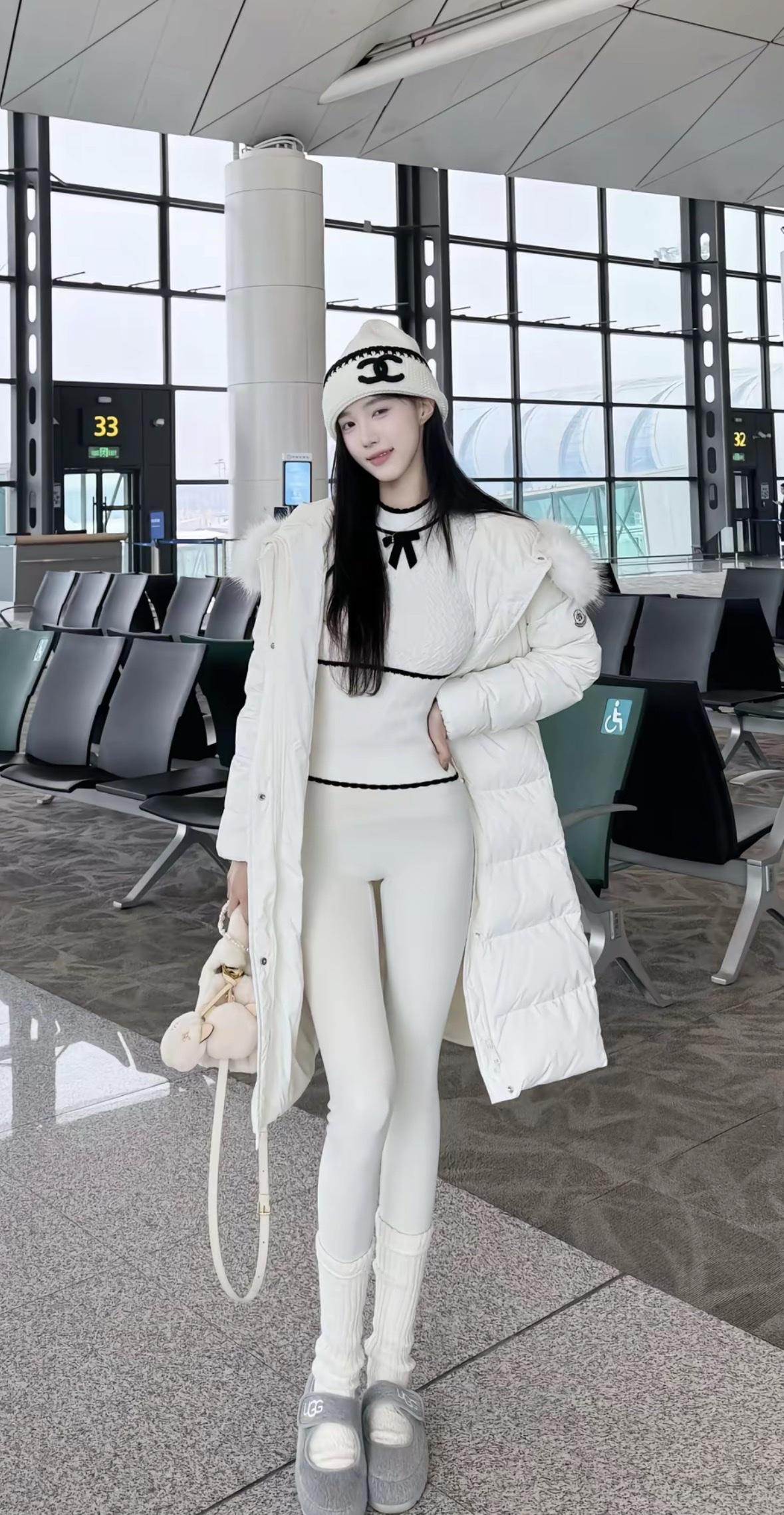 在机场的时尚少女，白色羽绒服搭配可爱毛绒包，轻松自在地等待航班。