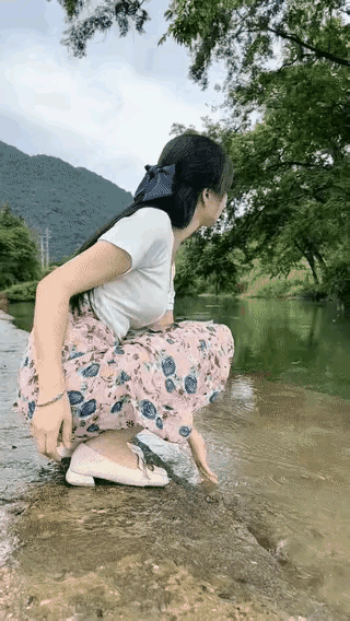 人杰地灵，山青水秀，一美女在河边戏水，好不惬意。