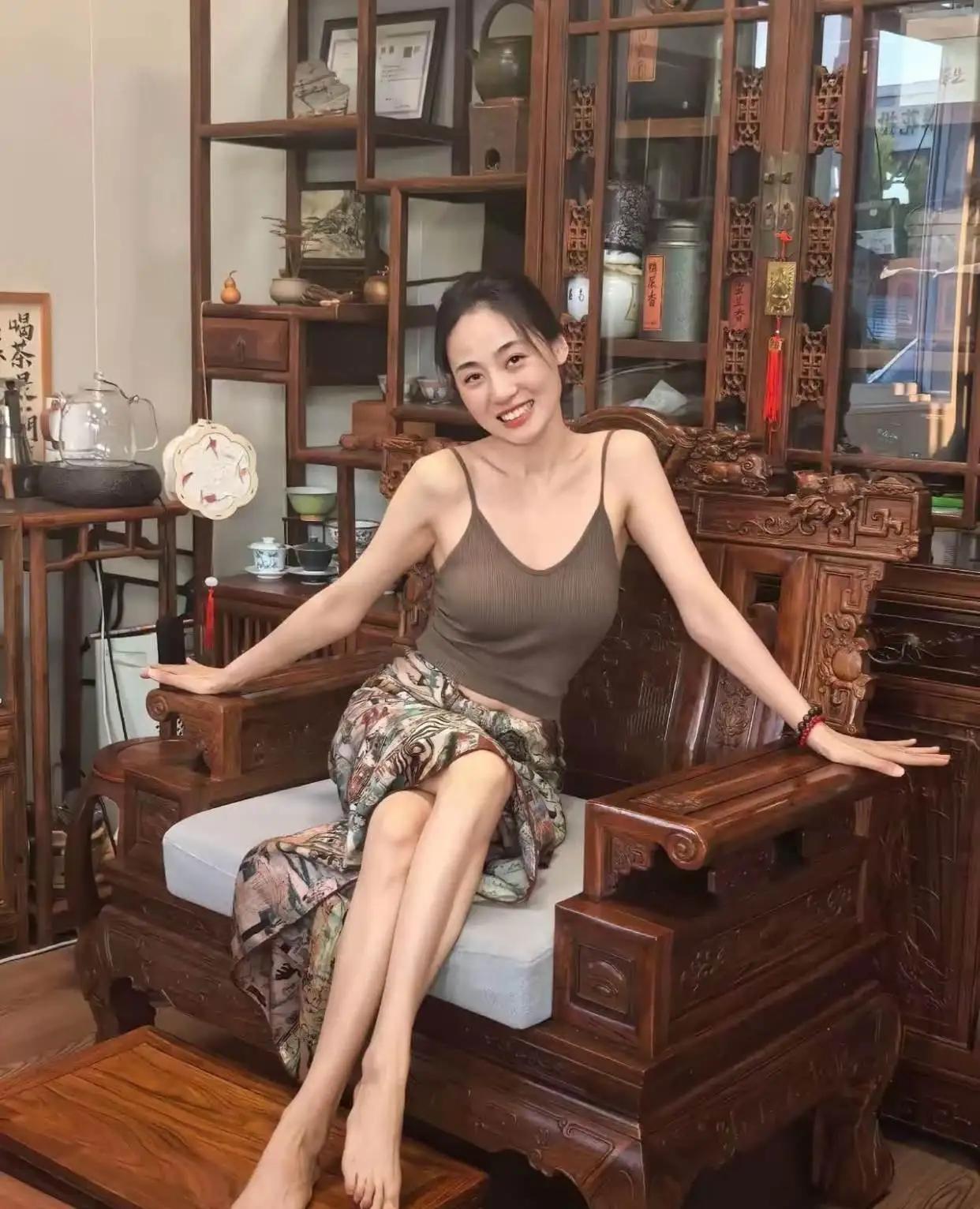 这位女士坐在古色古香的木椅上，笑容灿烂。