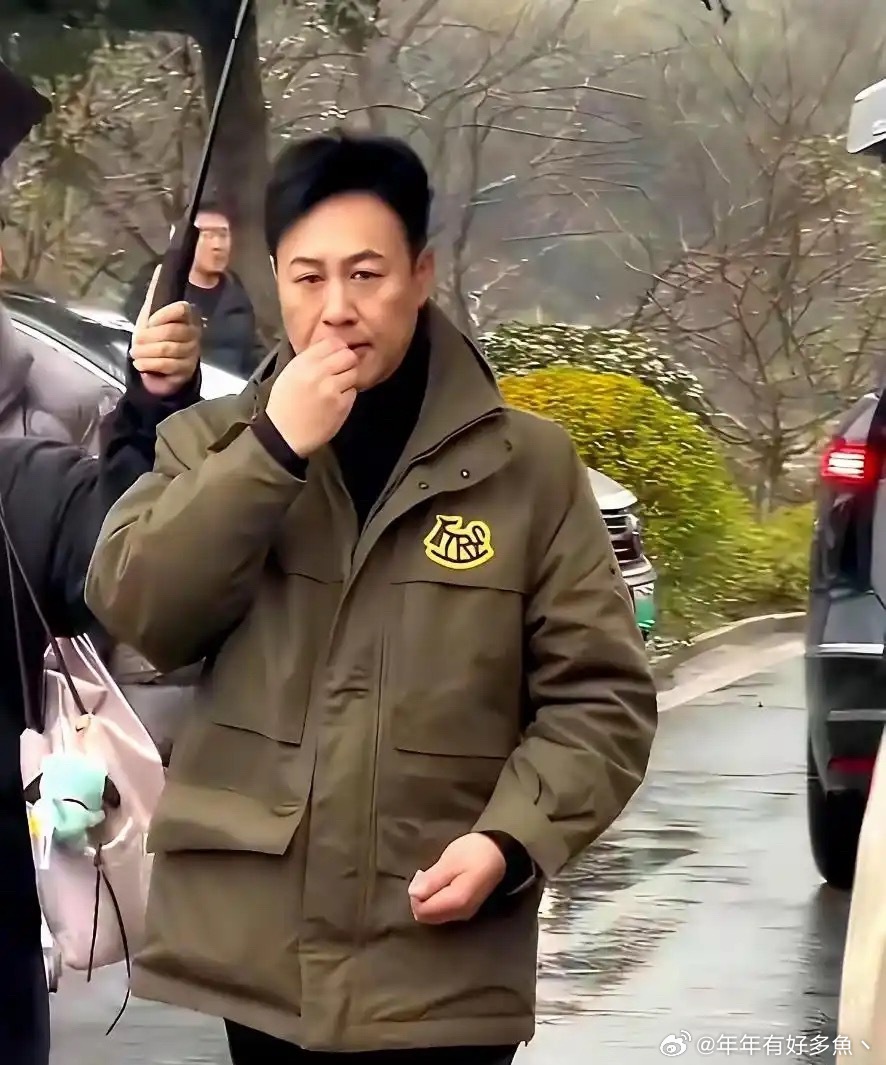 女助理半个身子淋着雨，张颂文却在伞下悠闲嗑瓜子。