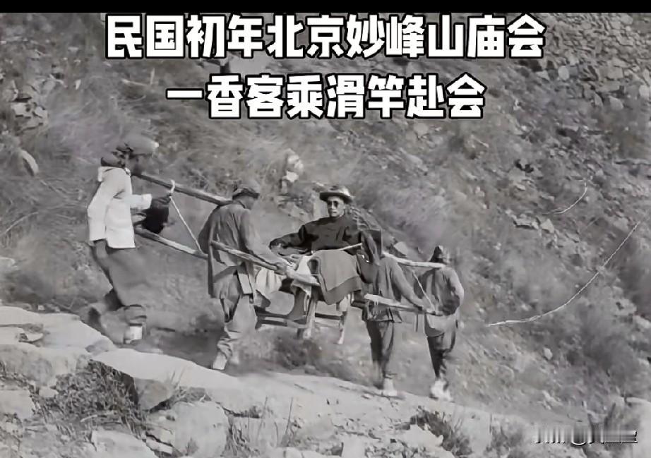 这是一张拍摄于清末民初北京妙峰山的老照片。四位轿夫抬着一乘简易的滑竿，正沿着