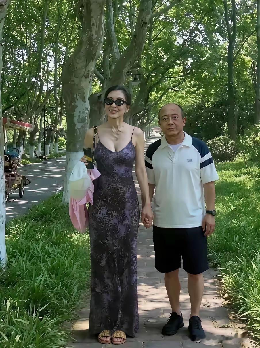 这个女的也真敢穿，大约只能在人少的公园里逛逛。牵着秃头老公的手，戴黑镜，笑得开心