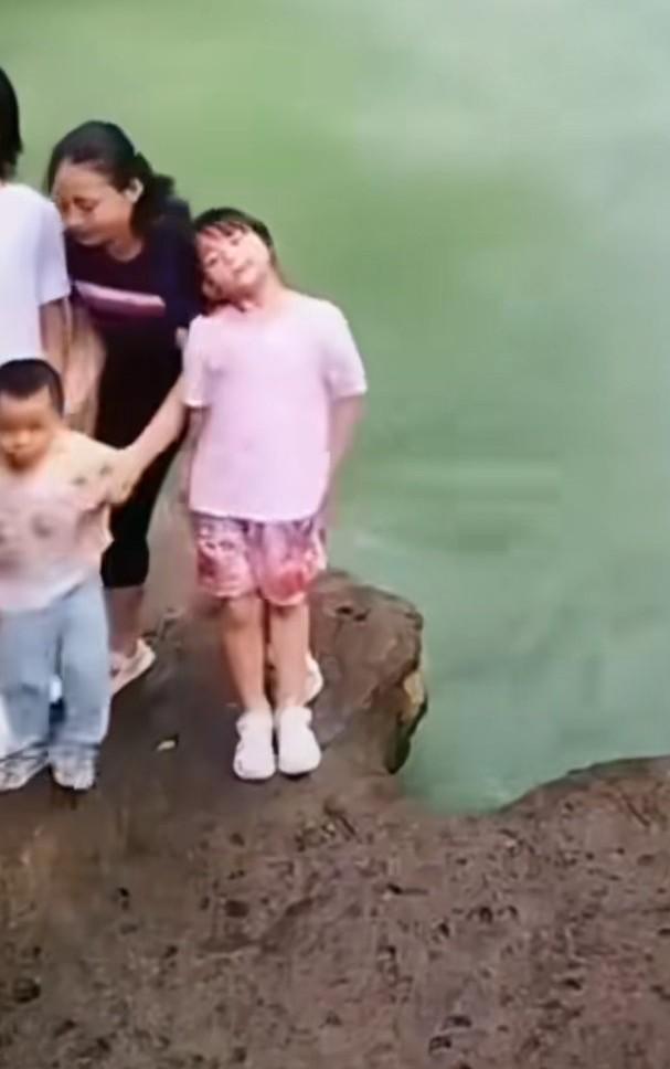 一家人站在水边合影，妈妈拽儿子时意外把女儿撞的掉了下去，急忙扔下儿子，跑到水