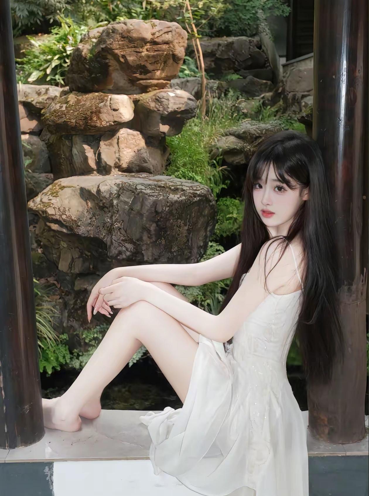 在绿意盎然的庭院中，她如仙子般静坐，裙摆轻拂，宛如梦境。