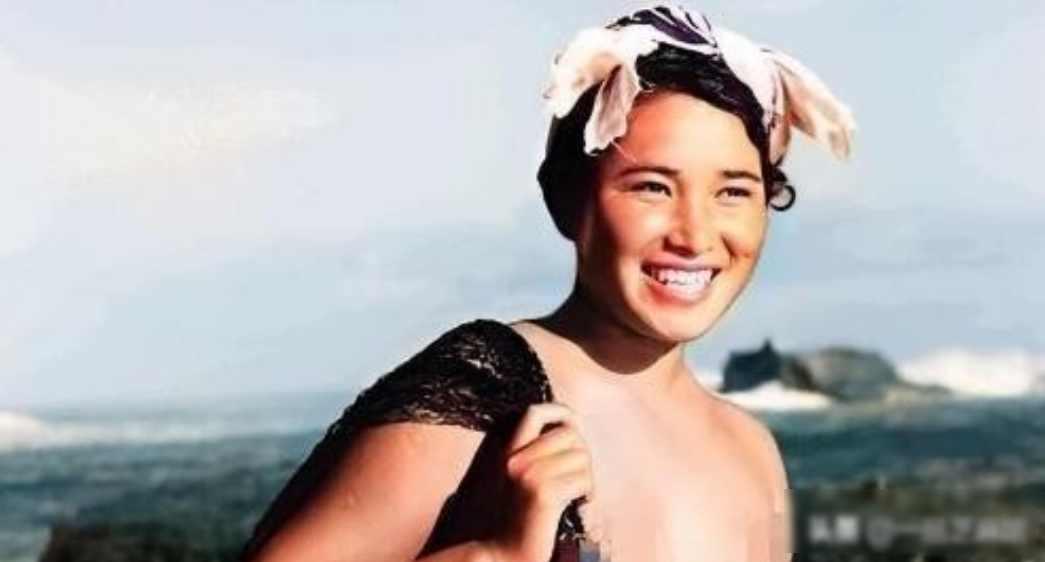 1955年，一名身体强壮的日本女人赤裸上半身，背着一个黑色的编织袋站在海边。这个