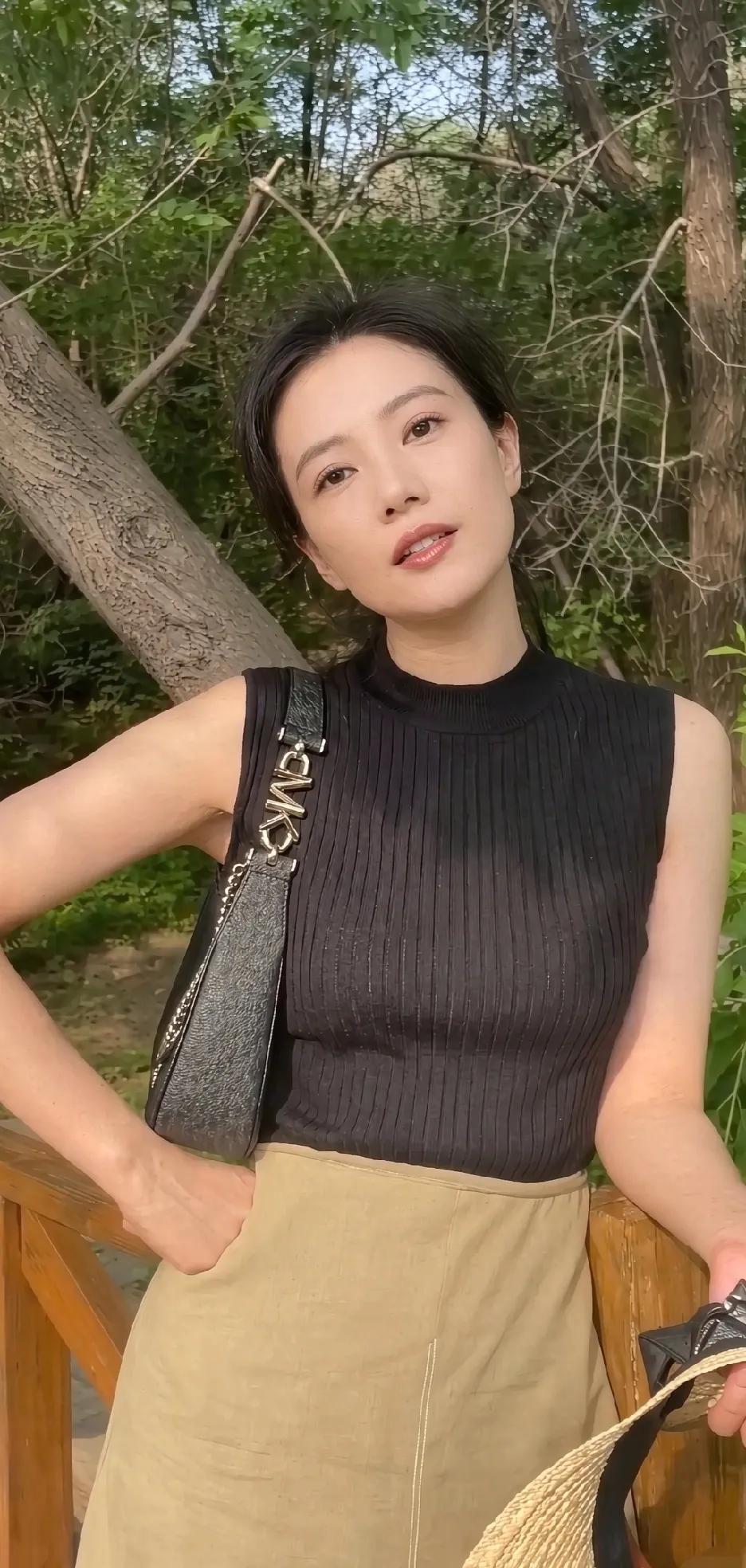 高圆圆户外随拍太耐看！黑色无袖针织背心搭配卡其半裙，简约干净。没有复杂的装饰，