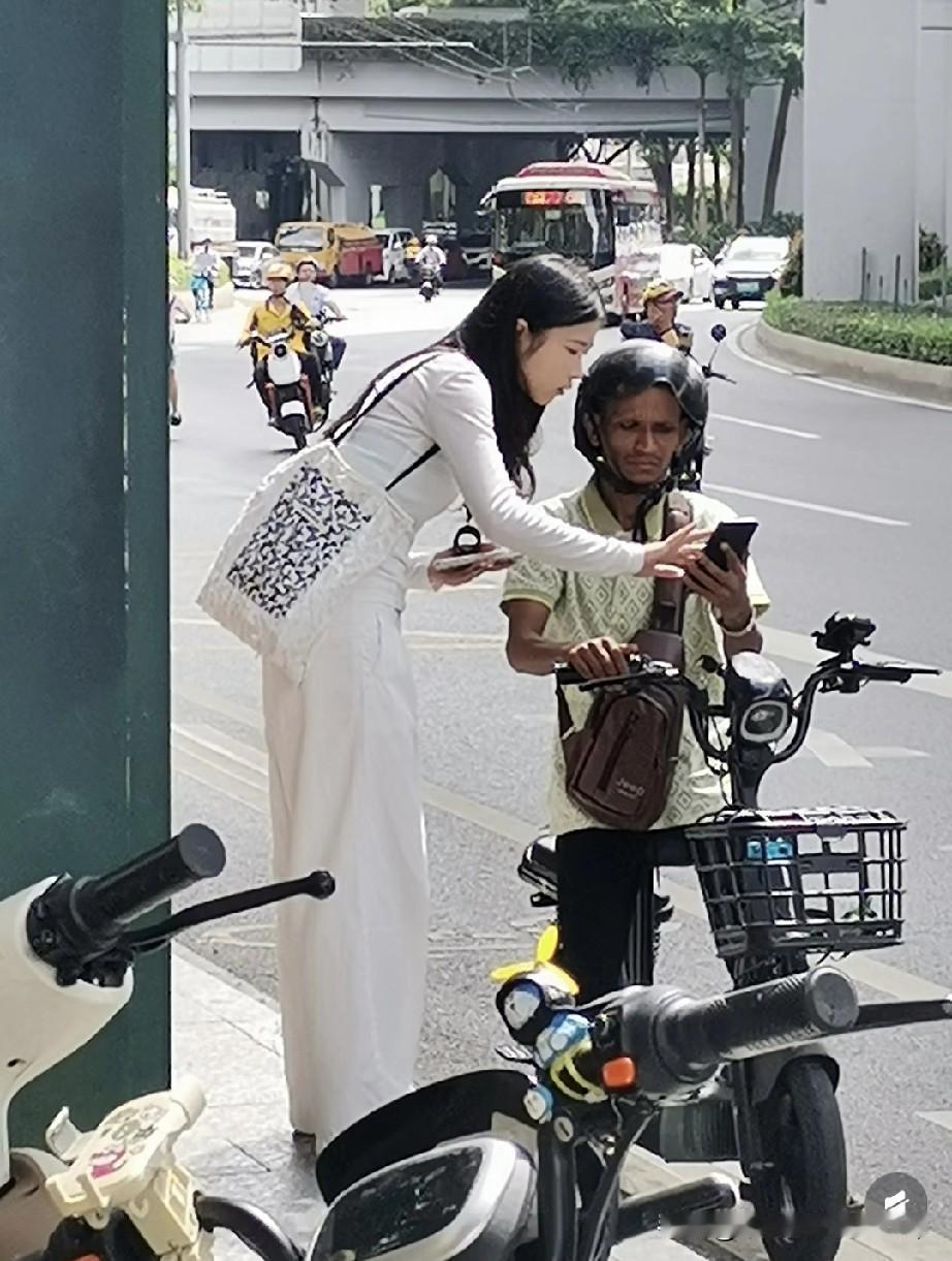 三元里现状，这个美女也真是单纯！在三元里街头，穿白裙的美女弯腰给骑电动车的