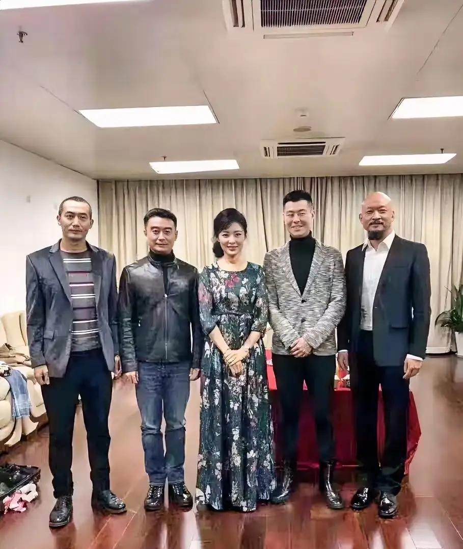 站在中间这位美女，她气质出众，端庄优雅，身穿藏蓝色暗花长裙，微微笑的她是谁？