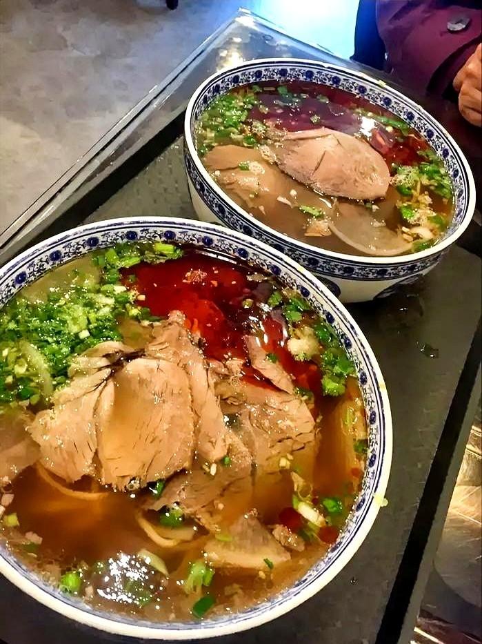 午饭高峰的短视频里一位大哥端着两碗25块的牛肉面发愣—汤面清透到能当镜子照，筷子