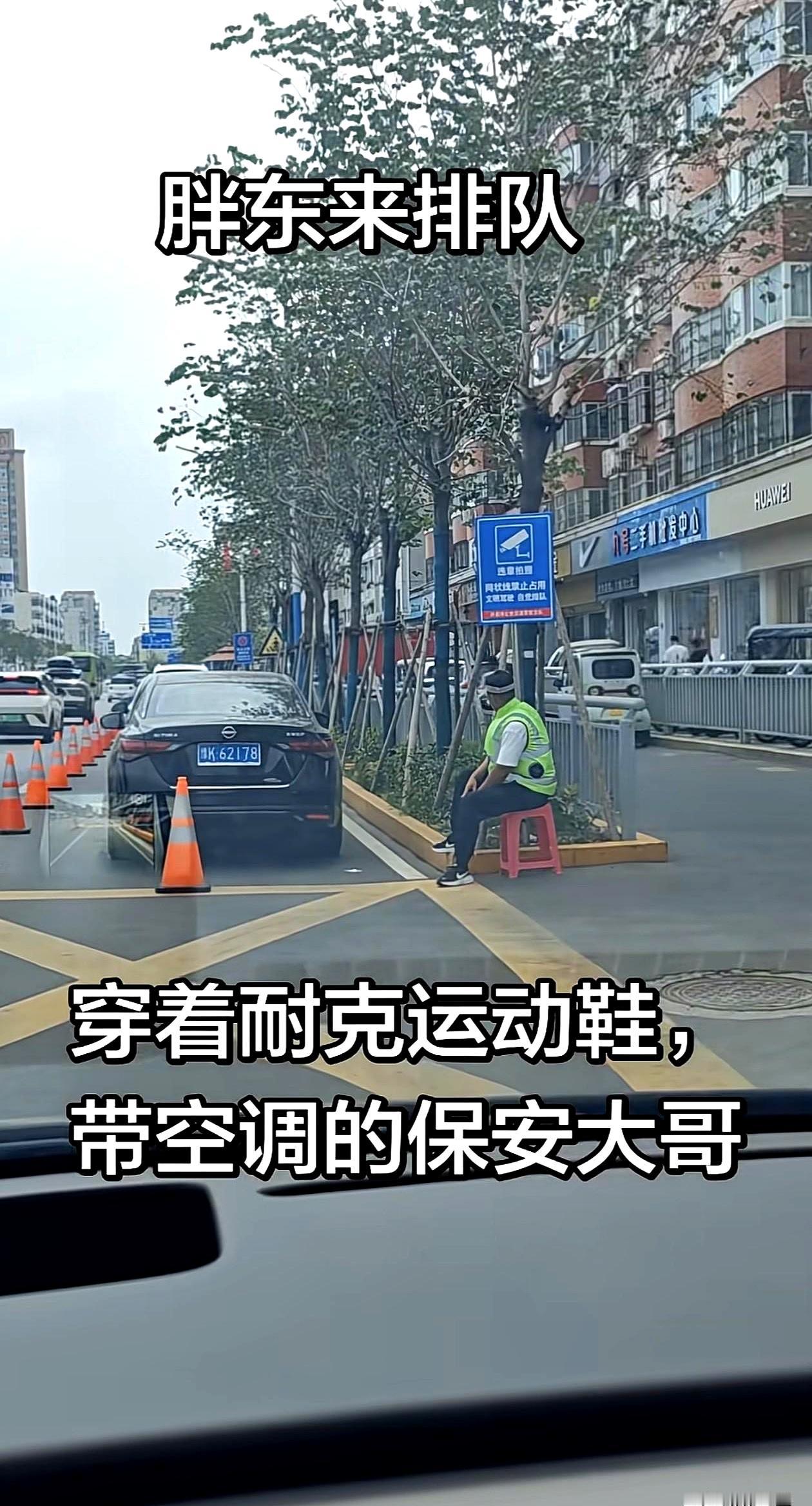 看见那位坐在小凳上的胖东来保安时，店里风扇正嗡着，他身上那件带风扇的“空调服”鼓