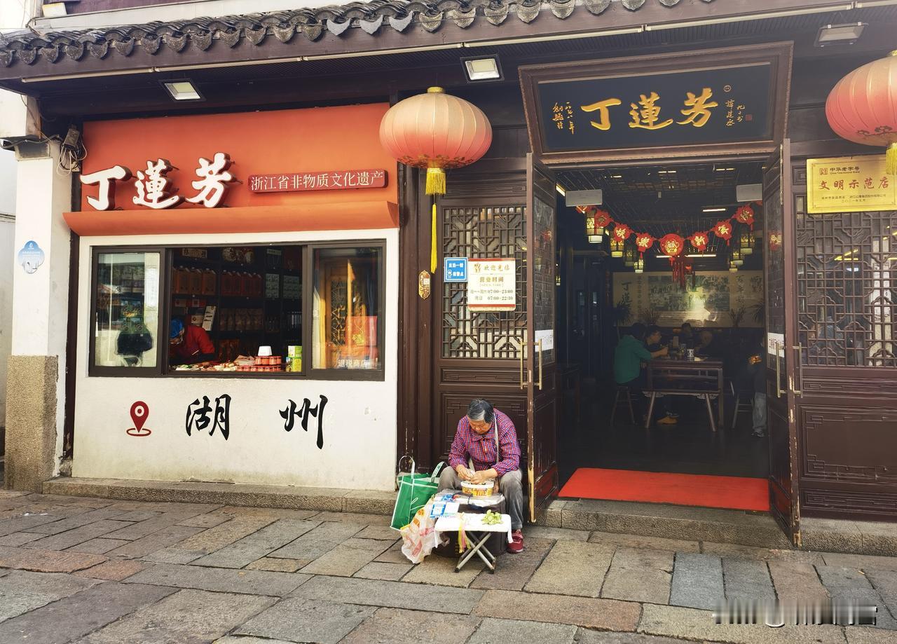 湖州衣裳街，百年老店“丁莲芳”门口，坐着一位头发花白的老奶奶。八十岁的年纪，背微