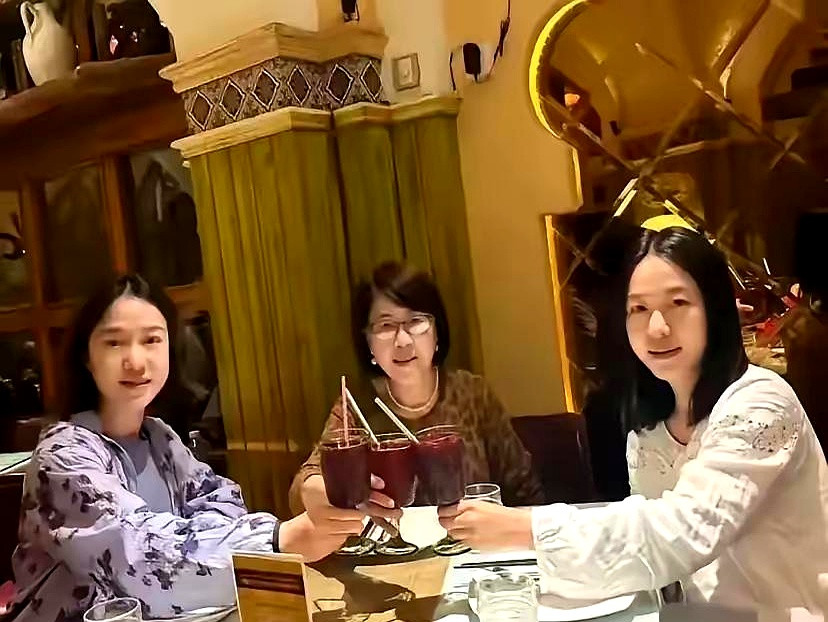 翁帆穿着紫色纱裙，和母亲、姐姐挨着坐在窗边。阳光落在她肩头，嘴角那点笑意，看着
