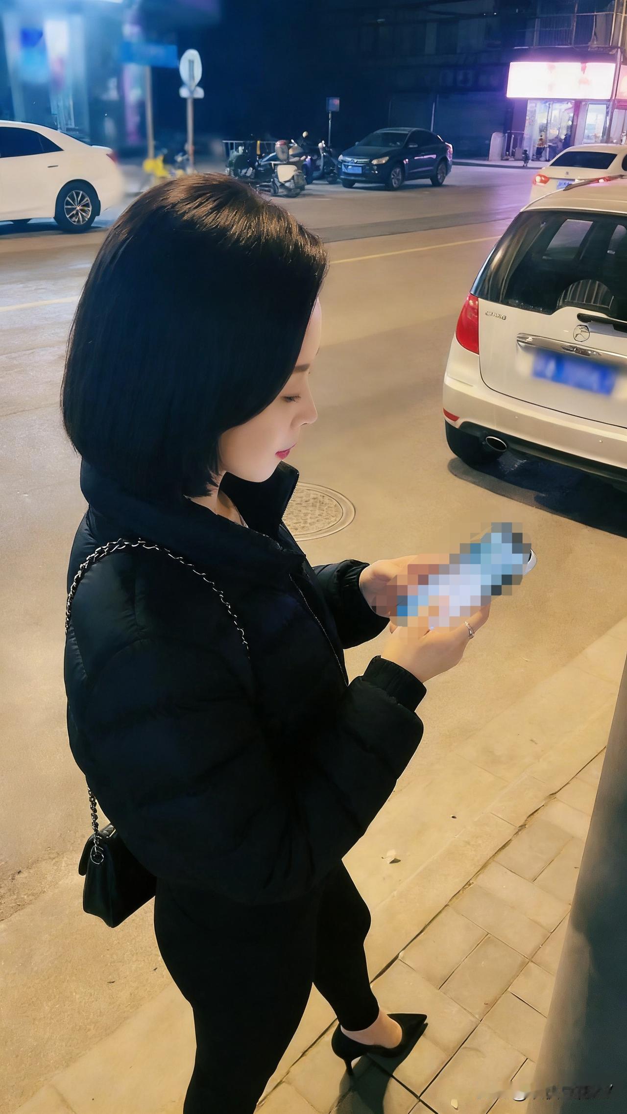 一位女士在路边看手机。