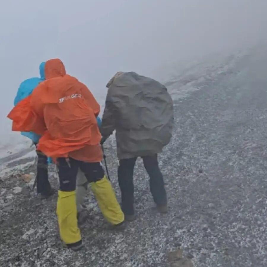 五一假期山西五台山突降风雪，狂风裹着雪粒，驴友抱团搀扶行走，不少人被困搭帐篷过夜