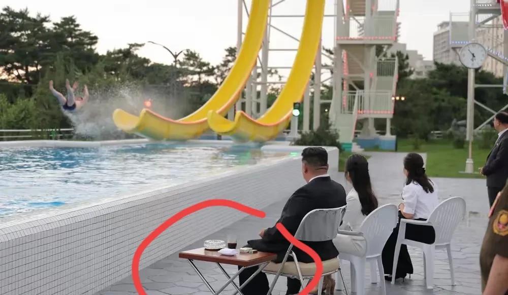 将军和女儿，夫人在元山葛麻海岸旅游区坐着观看人们水上乐园玩耍。将军座椅旁边小桌