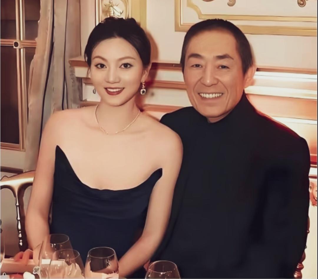 陈婷藏蓝缎面抹胸礼服的，端庄大气，笑容舒展，倒是见过大世面的张艺谋导笑的拘谨。