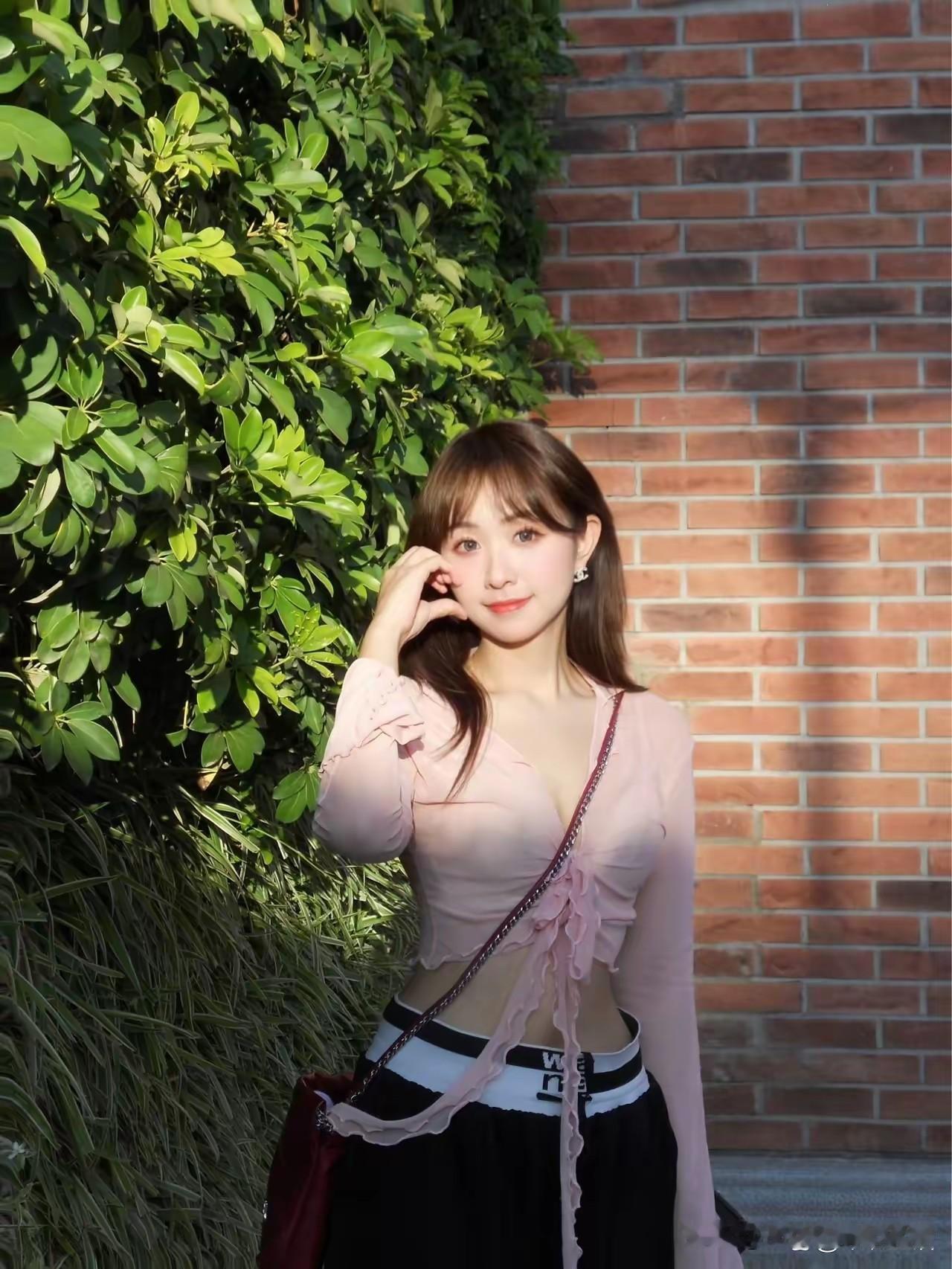 看到一个女孩在绿植旁拍照，阳光明媚，画面简直太美好。就像那个穿橙色裙子站在开花树