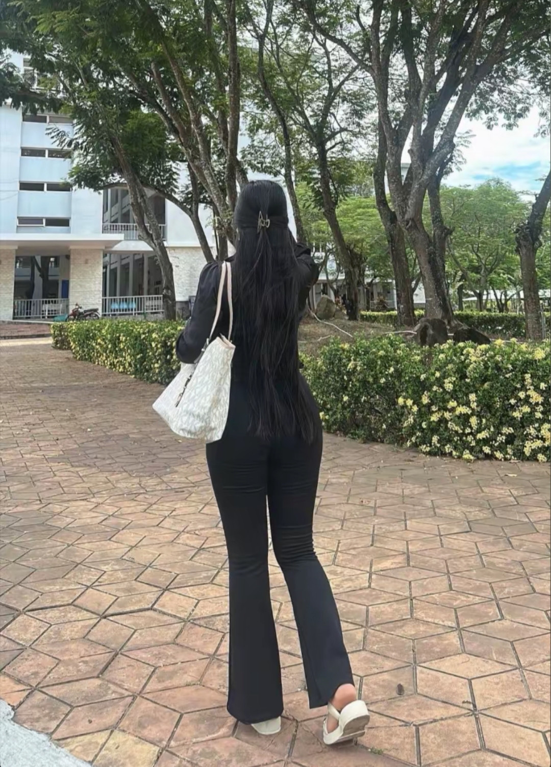 长发曳曳映晴光，步履悠然向远方。树影婆娑风正好，一身素黑亦疏狂。