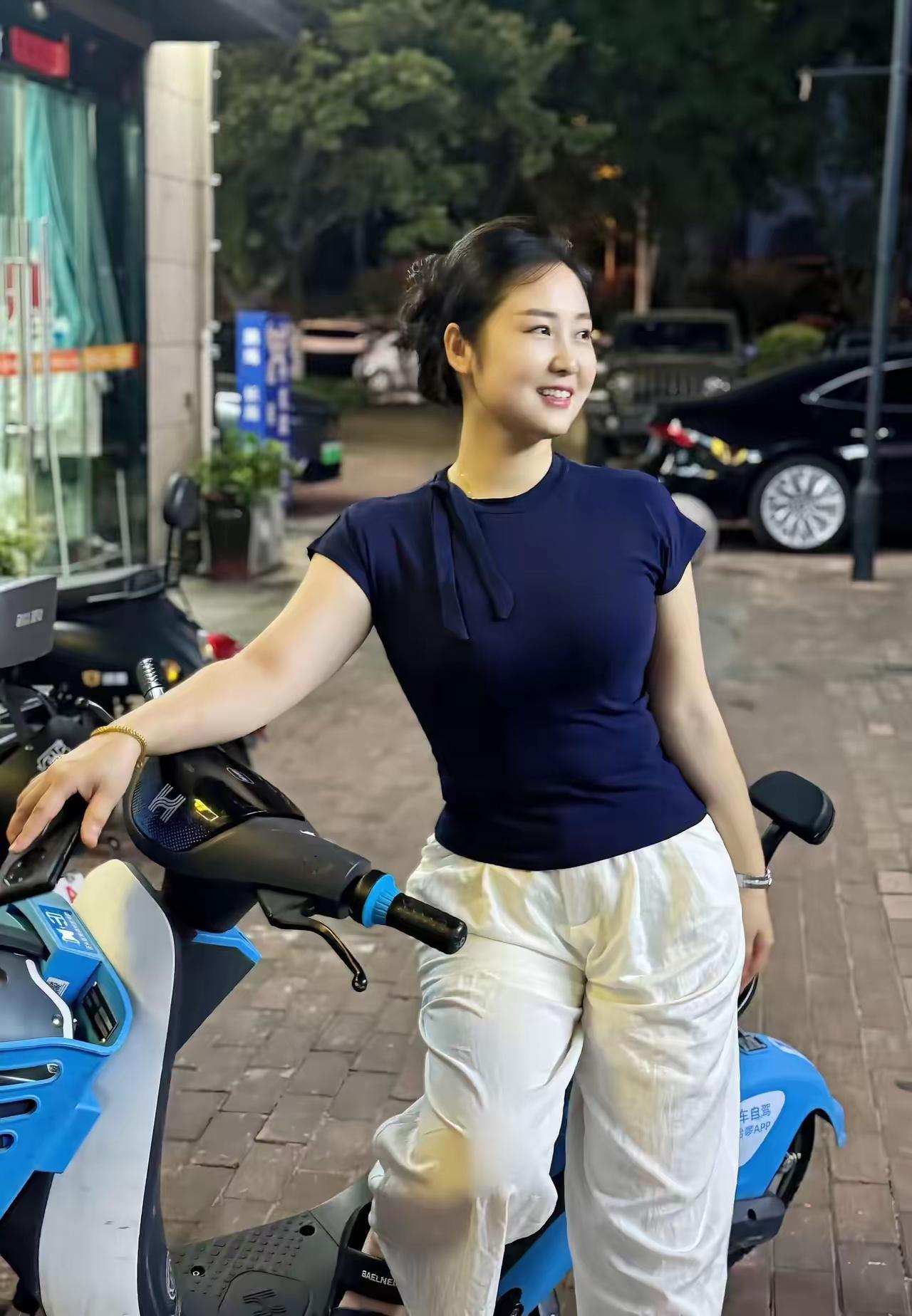 夜晚街头的时尚穿搭，蓝色上衣与白色裤子搭配，轻松自在。