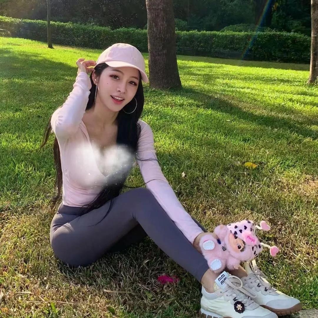 阳光明媚的公园里，甜美少女摆出可爱姿势，粉色帽子与白色运动鞋相得益彰。粉裙微笑写