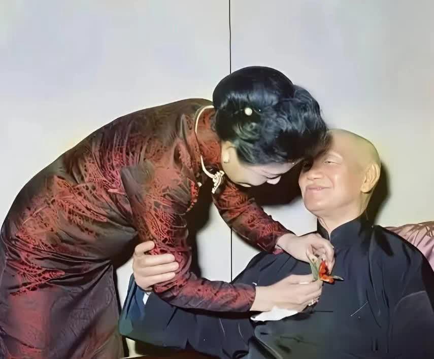 这是蒋介石88岁生辰的一个瞬间，宋美龄身着一袭典雅的暗纹旗袍，俯身专注，小心翼翼