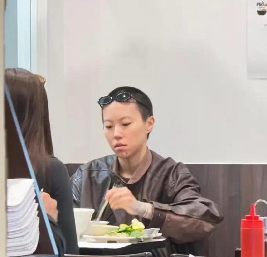29岁窦靖童在法国巴黎餐馆吃汤面时被偶遇，她留着寸头短发，下巴有纹身，中性打扮很酷。​