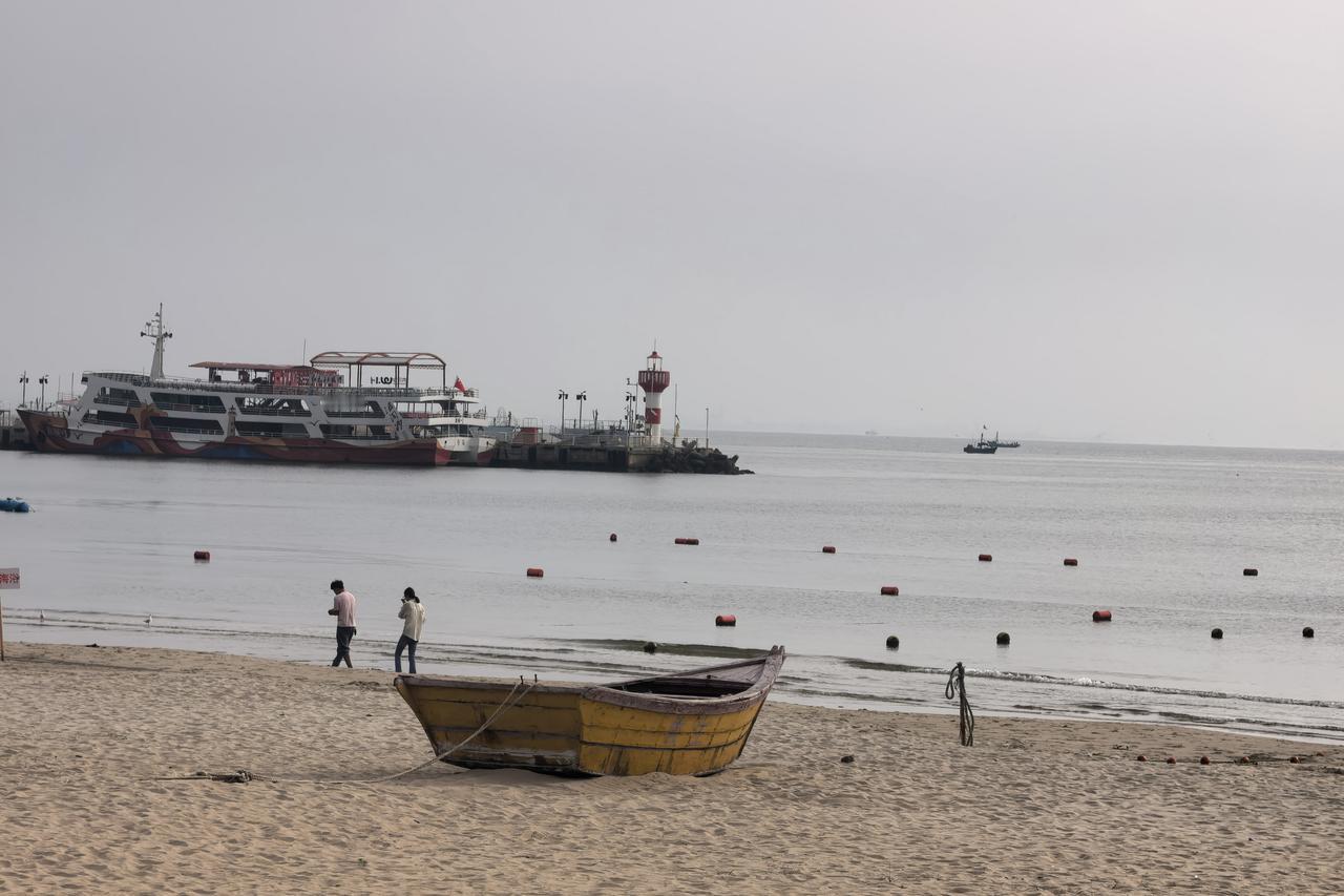 晨遇北戴河、海风漫清晨｜清晨漫步北戴河海岸，海面清浅平静，沙滩、渔船与灯塔错落相