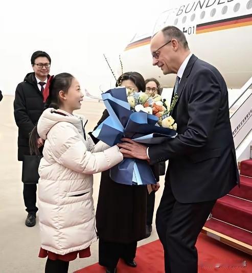 默茨来了，他的身材非常的高大，小朋友给他献上鲜花，他半弯着腰，显得特别的谦虚，这