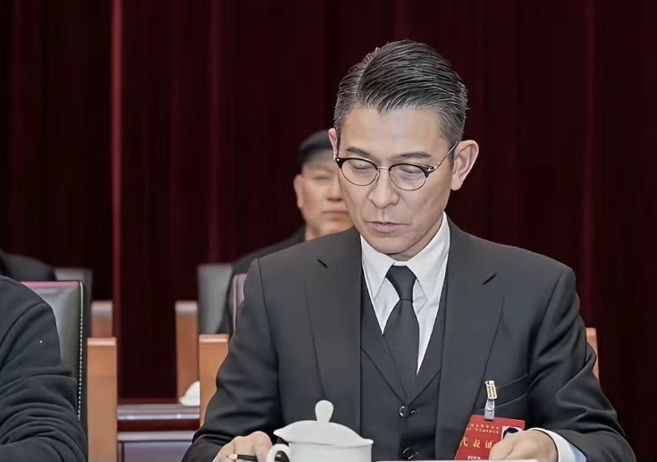 64岁刘德华再上央视新闻联播！画面中的刘德华一身干练西装，搭配白衬衣、黑领带，正襟危坐、精神抖擞，厅