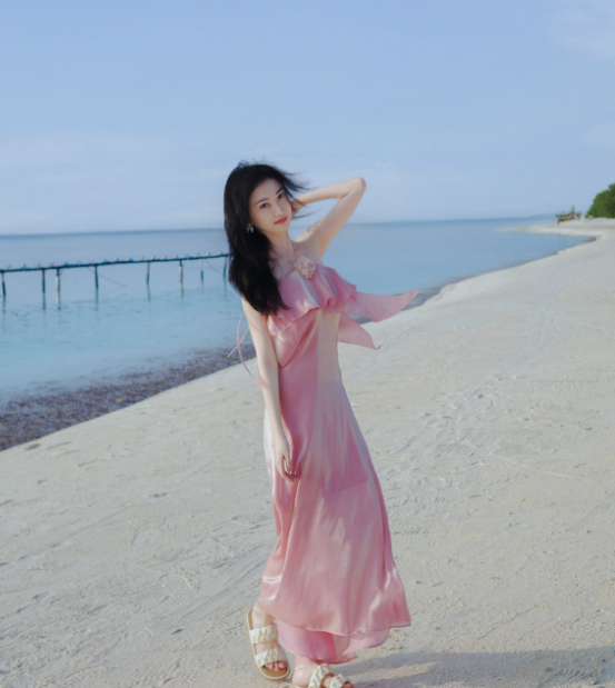 好久不见的景甜晒出了一组海边旅行大片身穿粉裙造型明媚又温柔，粉色衬托得她肤白胜