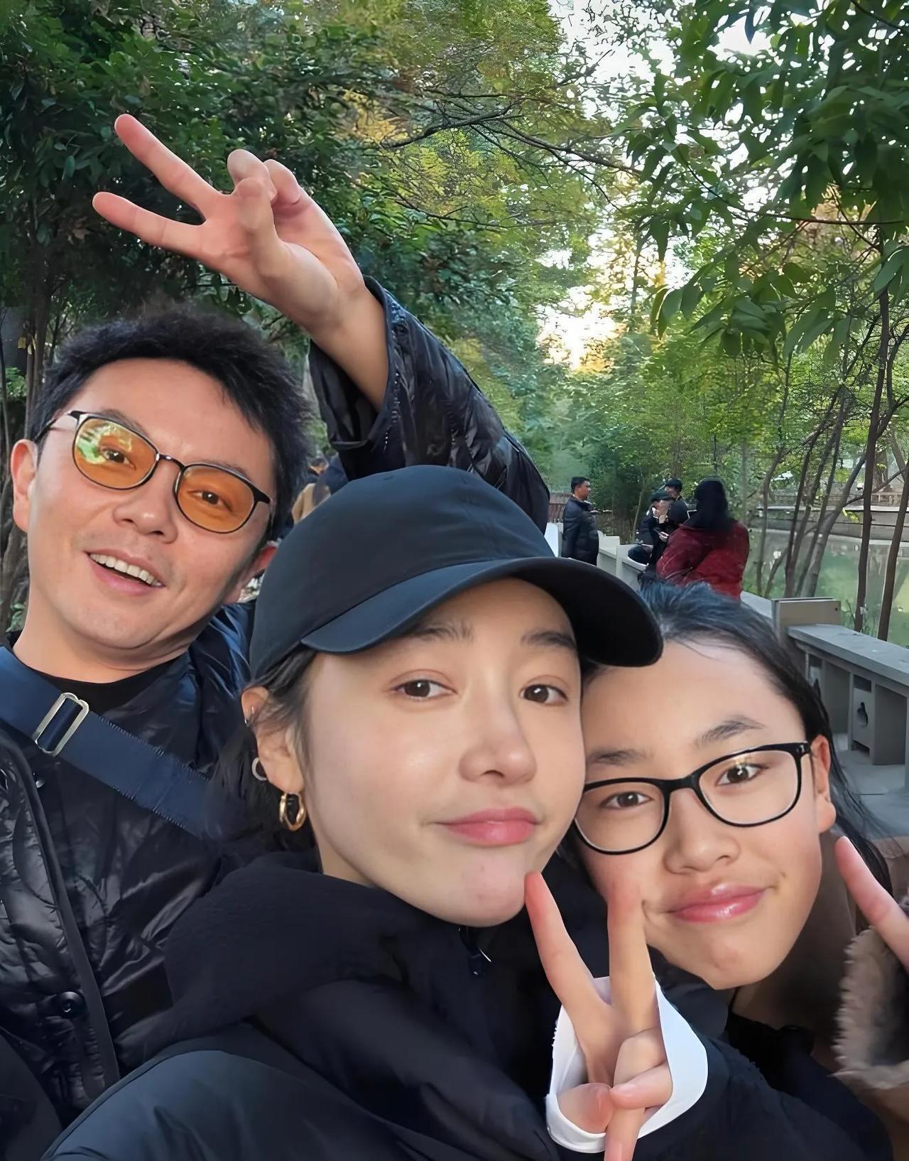 谢苗一家三口自拍照。他站在妻女后面比着剪刀手手势。戴着黑色帽子的就是他老婆何彦霓