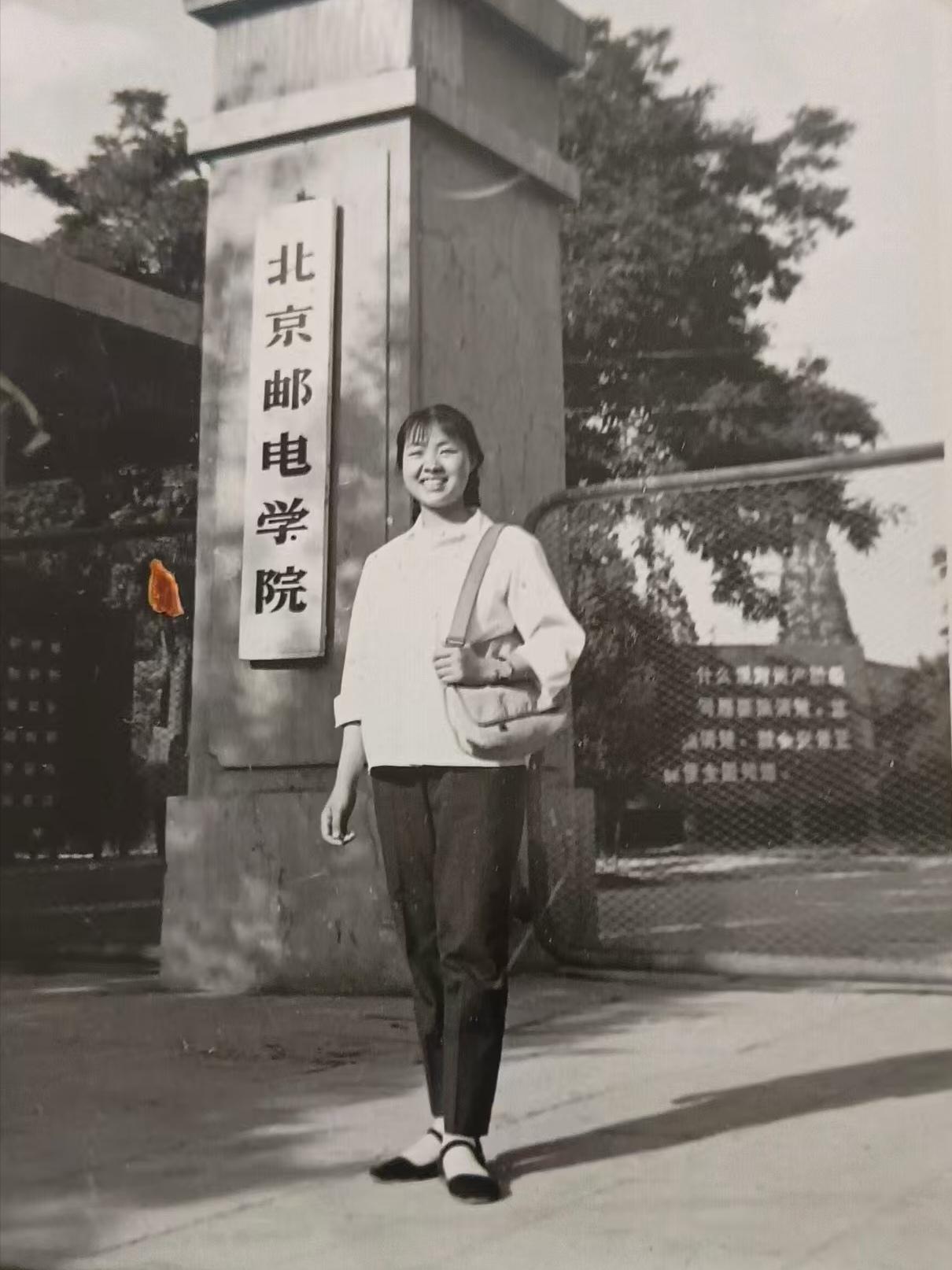 1978年，北京邮电学院大门前，一位女大学生笑容满面的拍照留念。北京邮电学校创