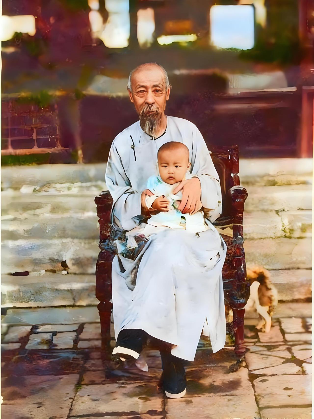 晚清时期，庆亲王奕劻身着浅色传统长袍，端坐在椅子上，神态平和。他怀中抱着年幼的小