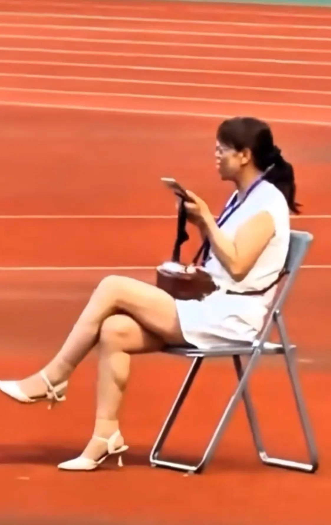 陇超赛场，全体起立奏国歌，一个女人翘着二郎腿坐在椅子上，抬头看了看唱国歌的人，嘴