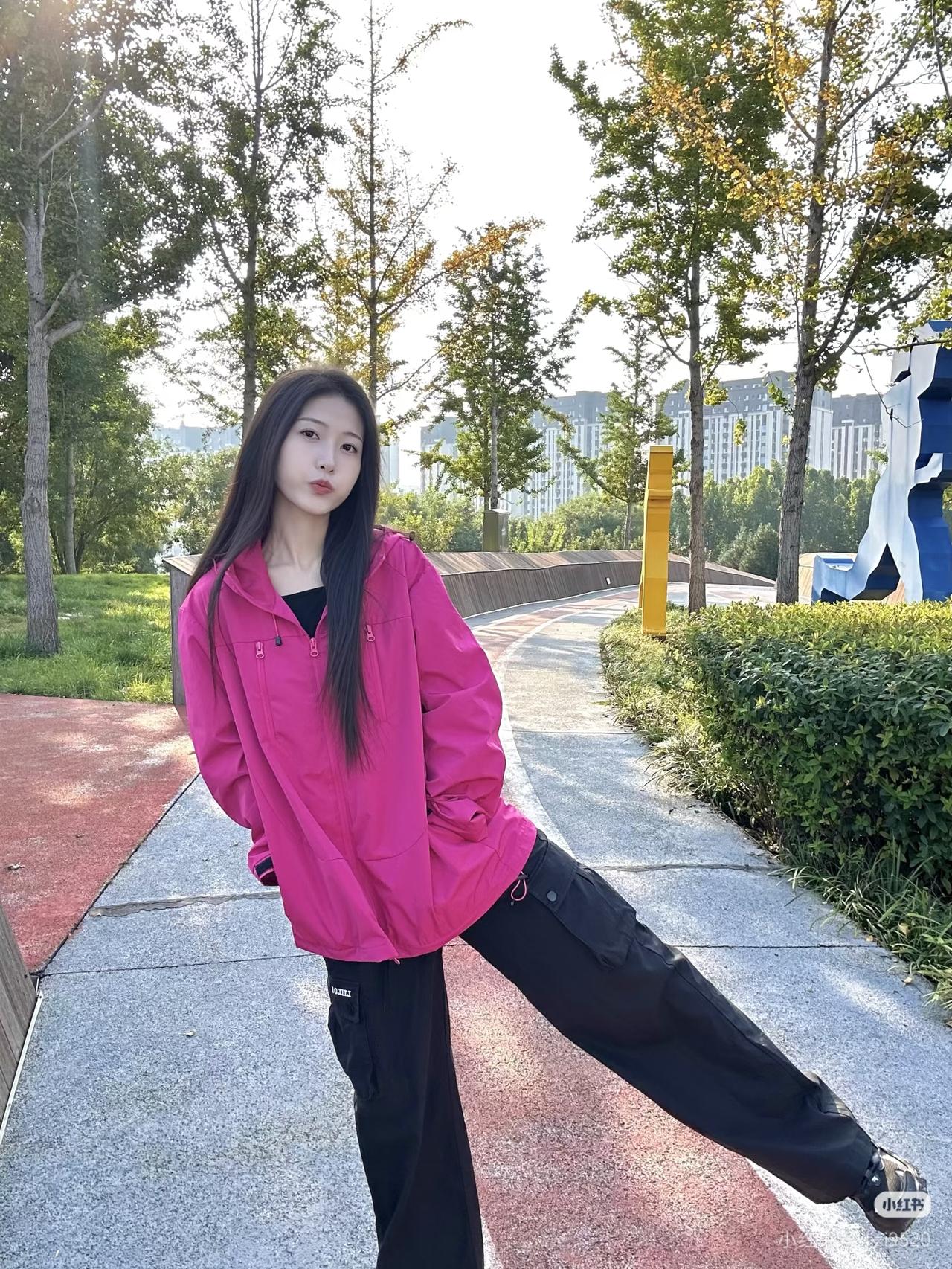 粉衣少女倚树旁，轻抚发丝意自闲。