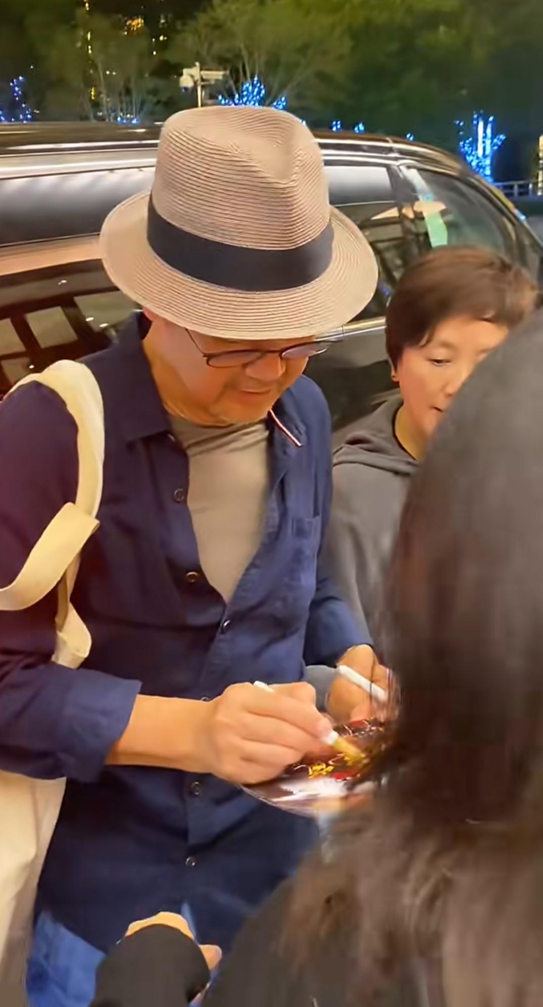 张国立演出离场，网友围住签名，邓婕紧紧牵着张国立的手全程陪伴。张国立