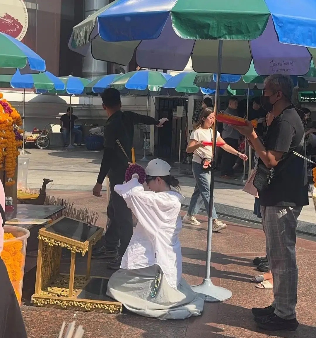 戚薇在泰国跪拜四面佛祈福，她打扮休闲又大方，她穿着一身白色衣服，在大热天下跪上香