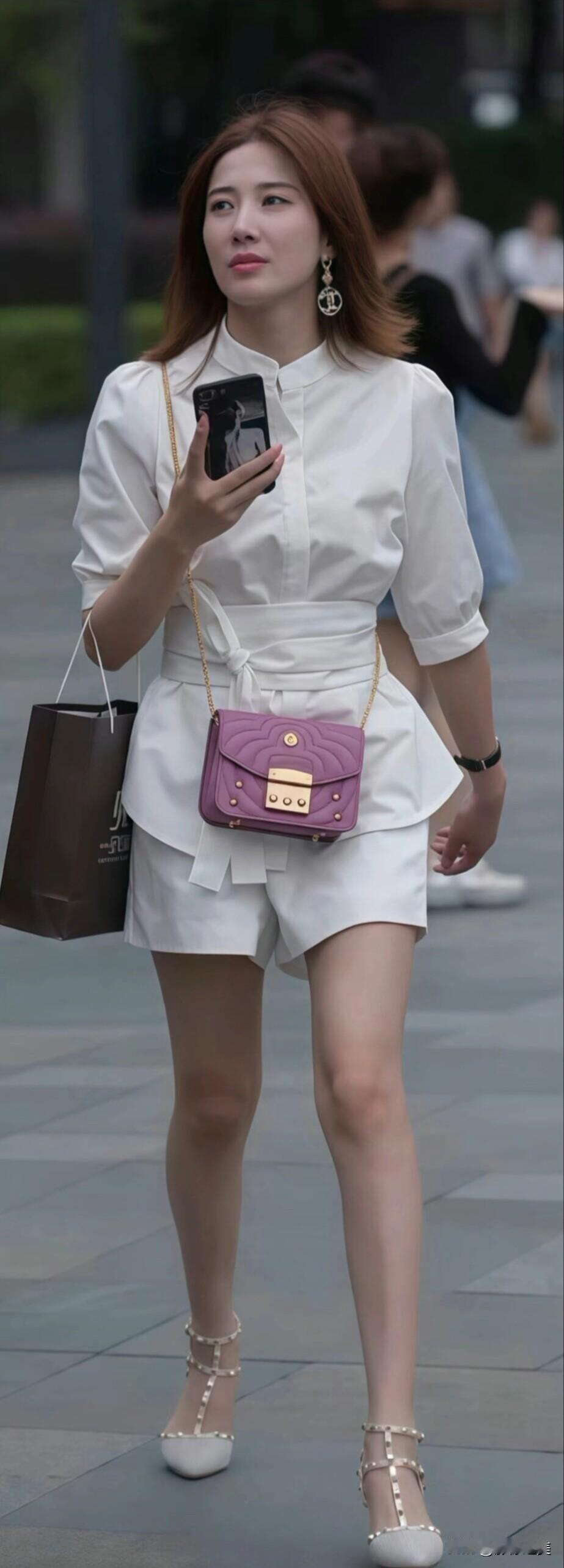 街头偶遇一位小姐姐，一身白色套装利落又显腿长，紫色小包当配饰，瞬间点亮了整体造型
