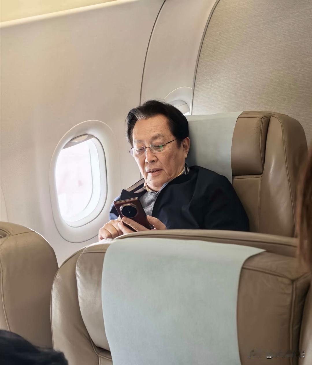 73岁唐国强在飞机上被偶遇，他坐在头等舱，翘着二郎腿看报纸，一副领导出行的派头，