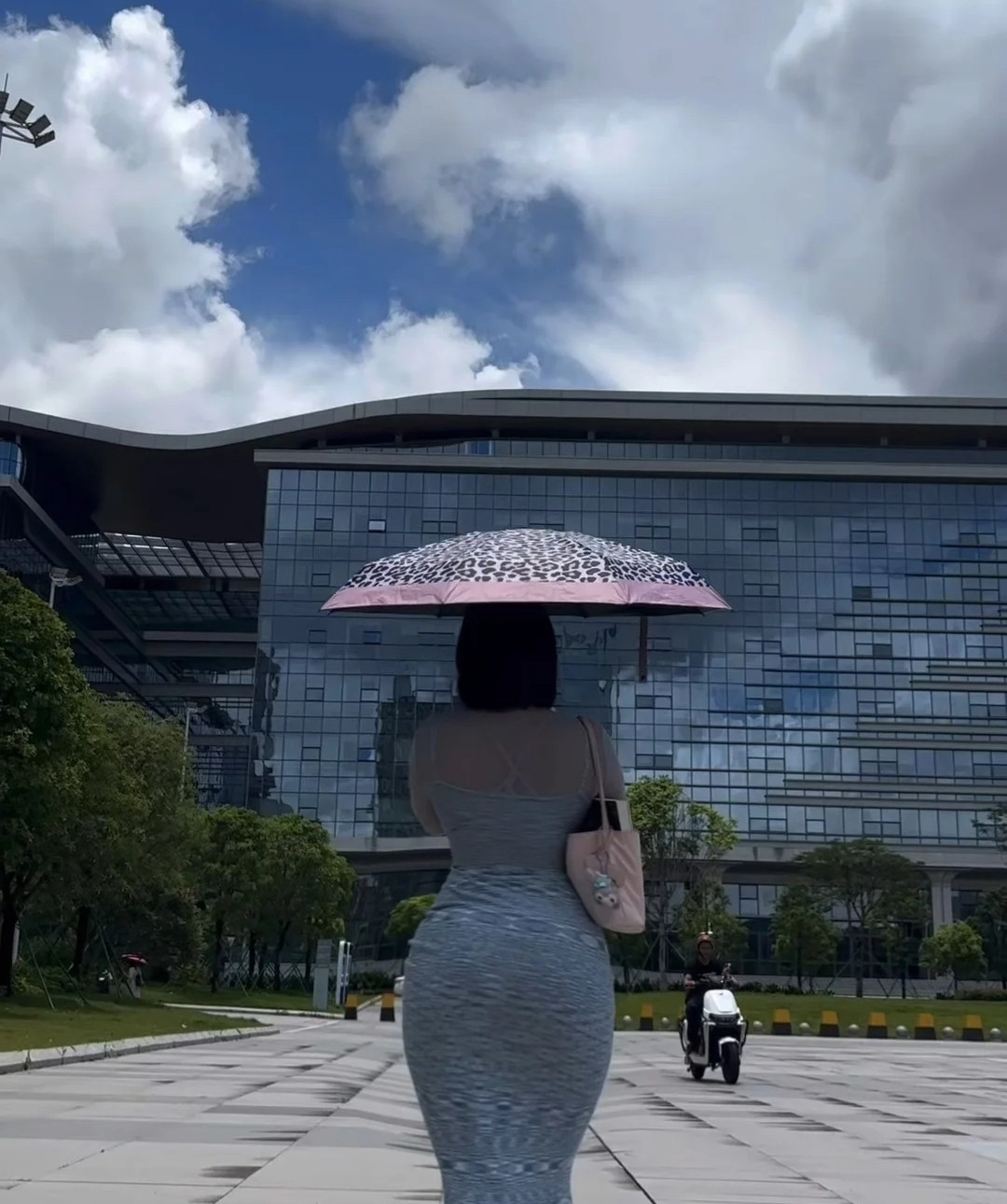 撑伞漫步，裙摆随步伐轻晃，身旁电动车驶过，风里藏着夏日的自在🌤️