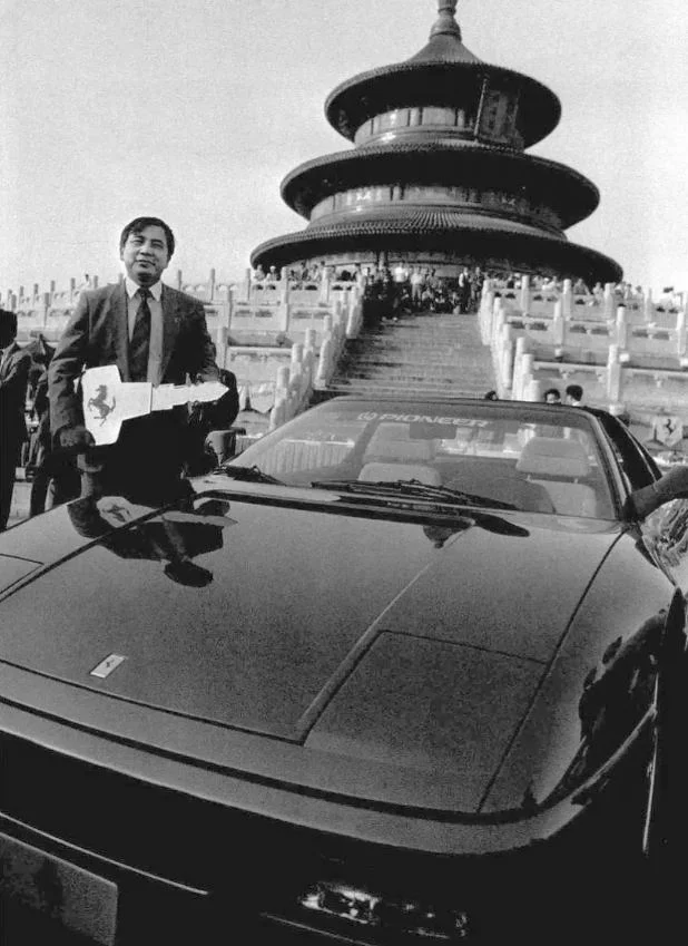 1993 年 5 月 8 日，北京天坛祈年殿前，富豪李晓华站在爱车旁...
