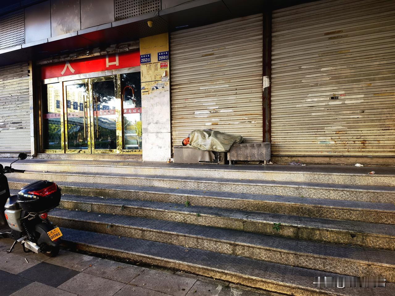 11月14日，早上7点18分温州，瓯江大厦一楼石凳上一男子躺在塑料编织袋里鼾