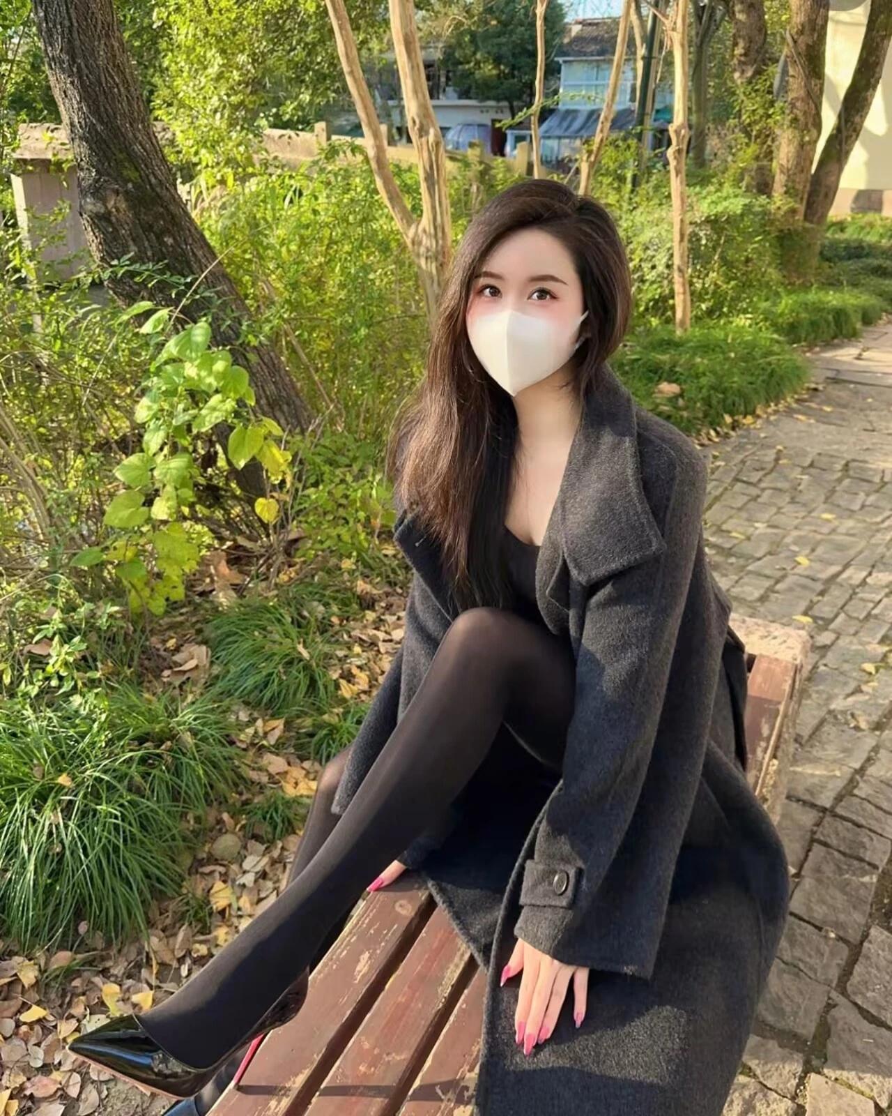 秋阳裹着风，落在大衣的褶皱里。长椅接住裙摆的松弛，黑丝与高跟鞋，是独属于这个季