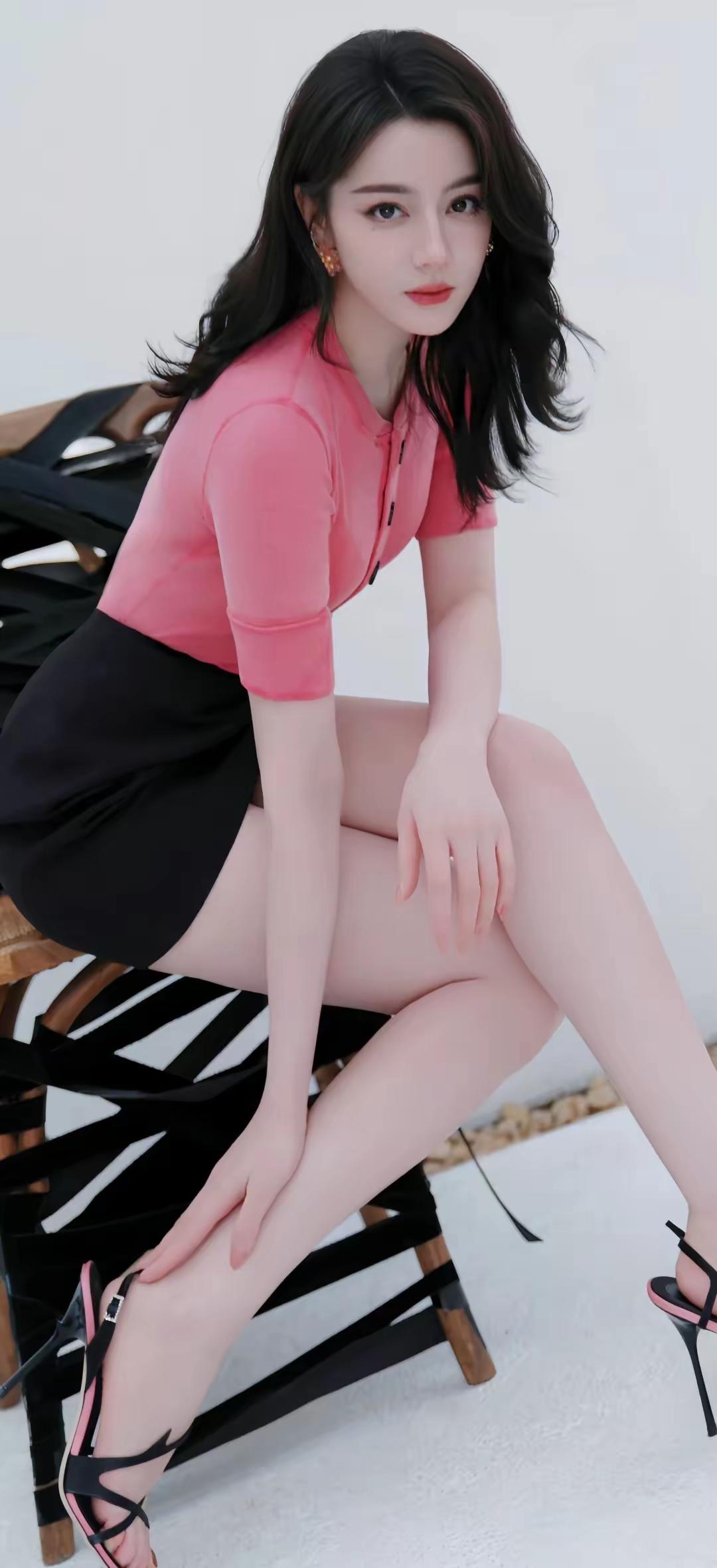 蜜桃粉针织衫勾勒曼妙曲线，搭配利落黑半裙，迪丽热巴将甜与飒完美融合。大波浪卷发衬