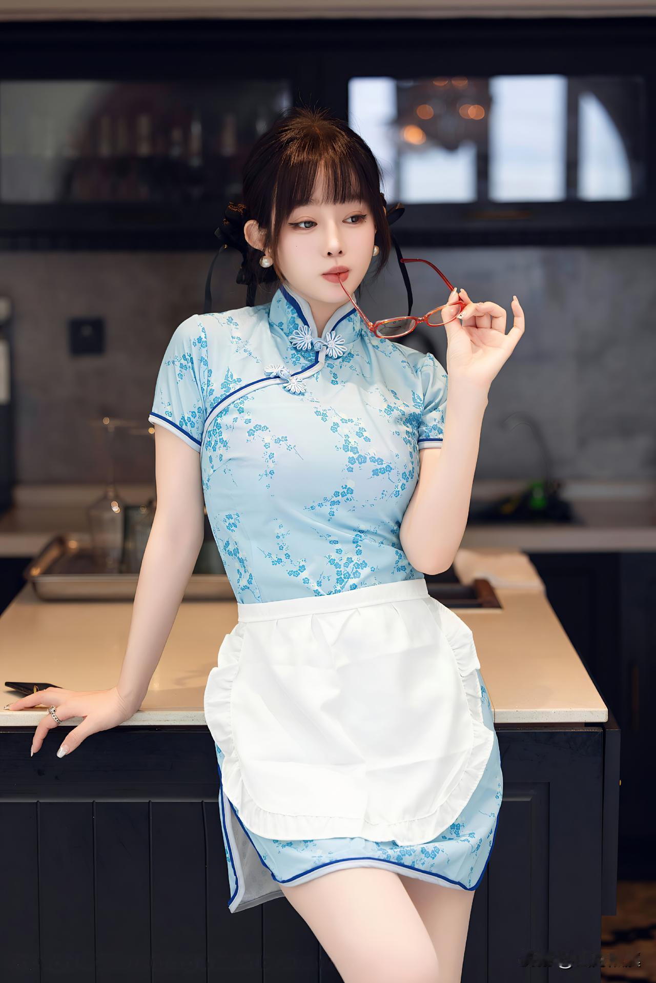 浅青瓷色裹着江南的细碎花影，围裙轻垂时，厨房的烟火气都软了几分。红框眼镜半掩眸色