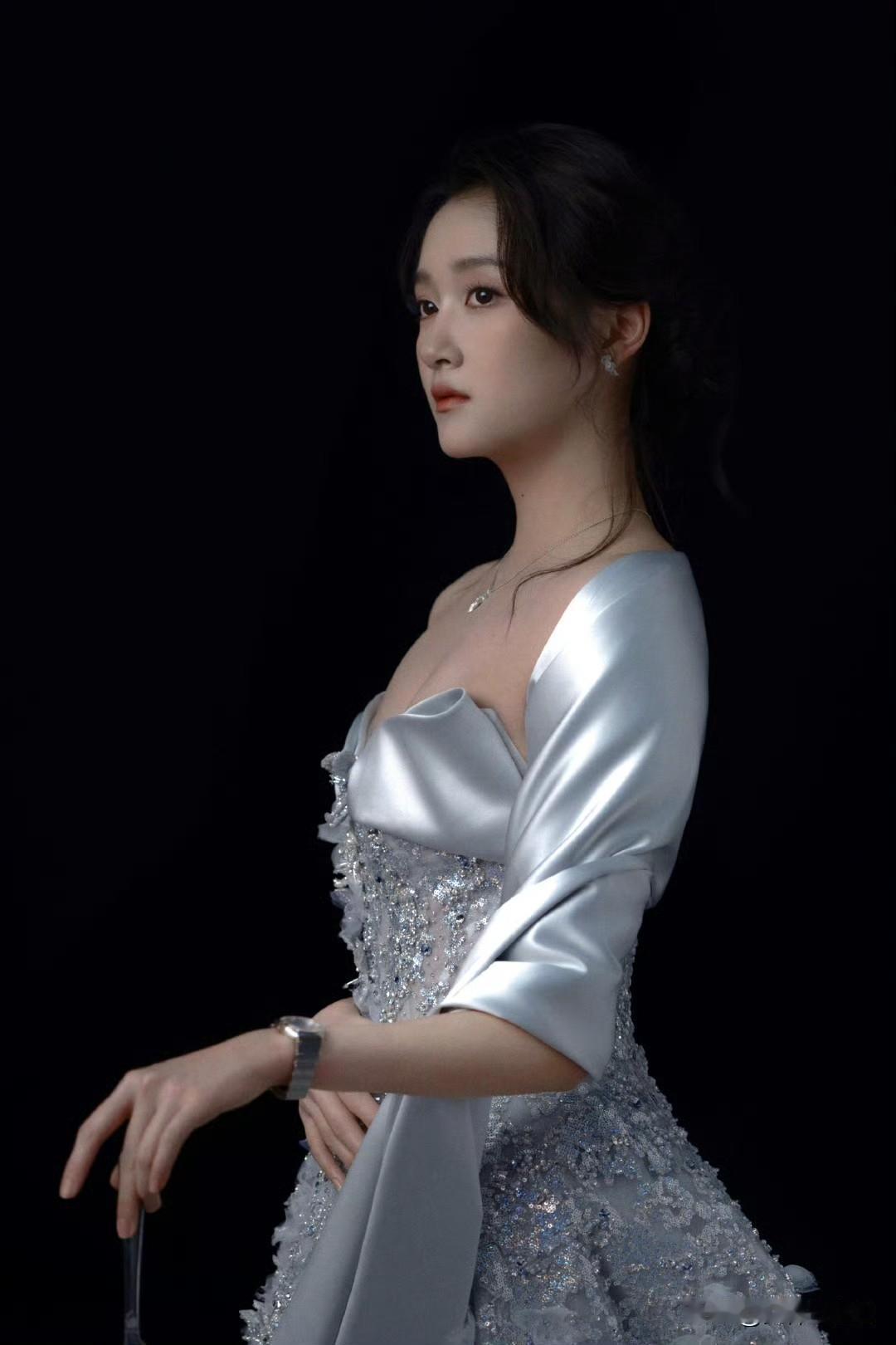 她穿着闪亮礼服，优雅地站着。