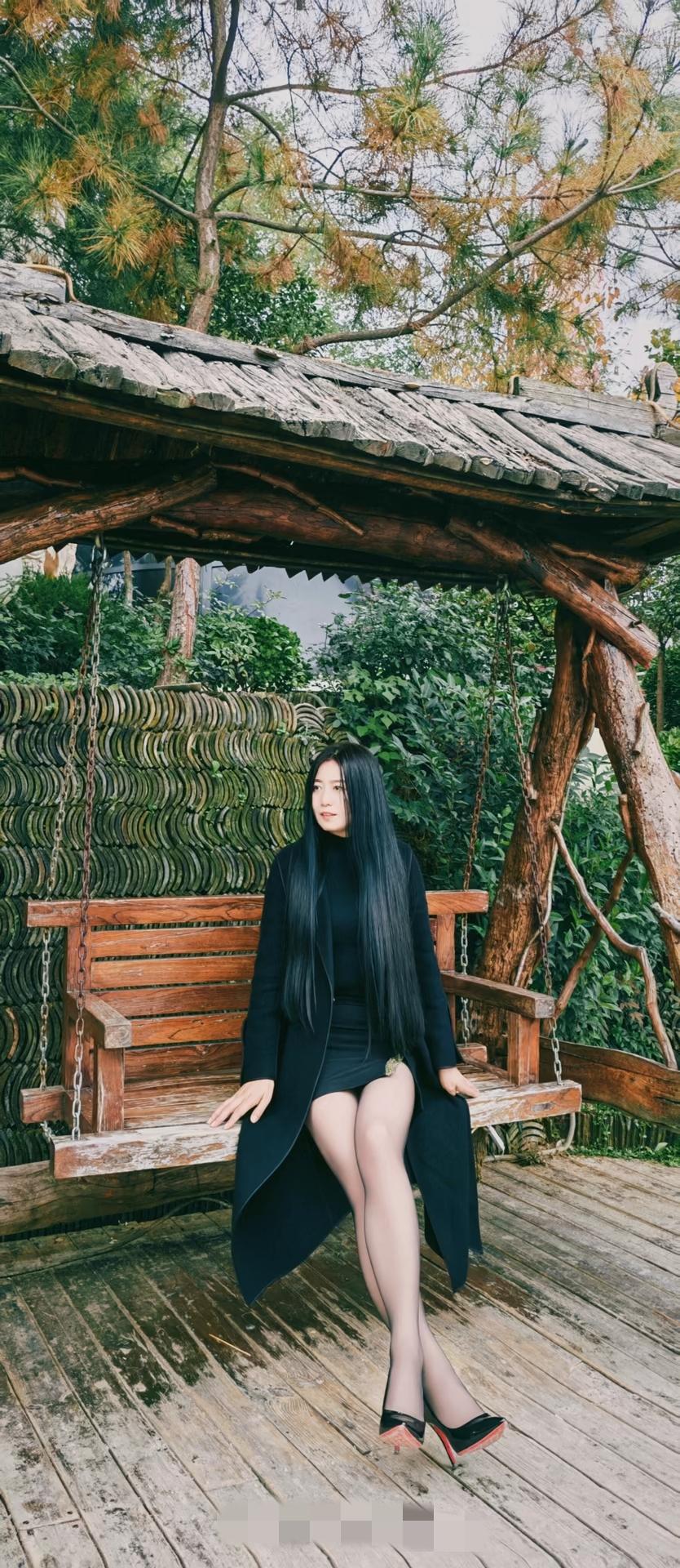 秋日森林中的优雅时光，黑衣女子坐在木制秋千上，静享宁静。御姐高跟鞋大长腿
