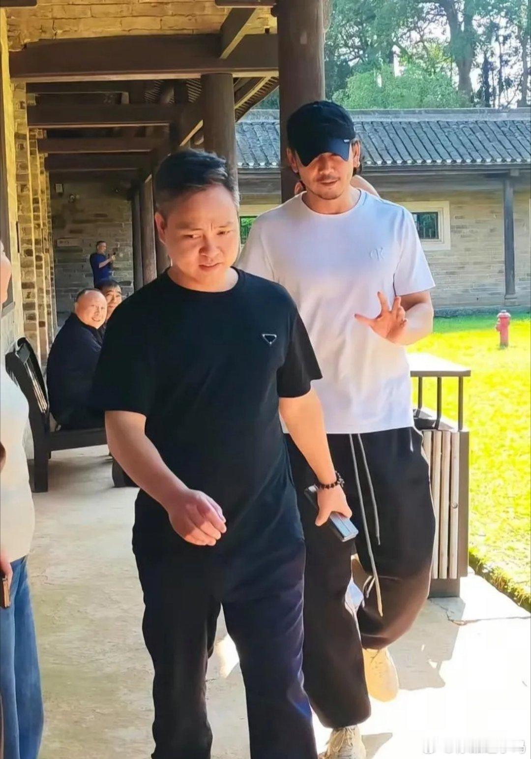 型男杨烁在湖南乡村游玩，头发卷曲，胡子拉碴，身穿白色圆领T恤衫黑色运动裤，裤腰上